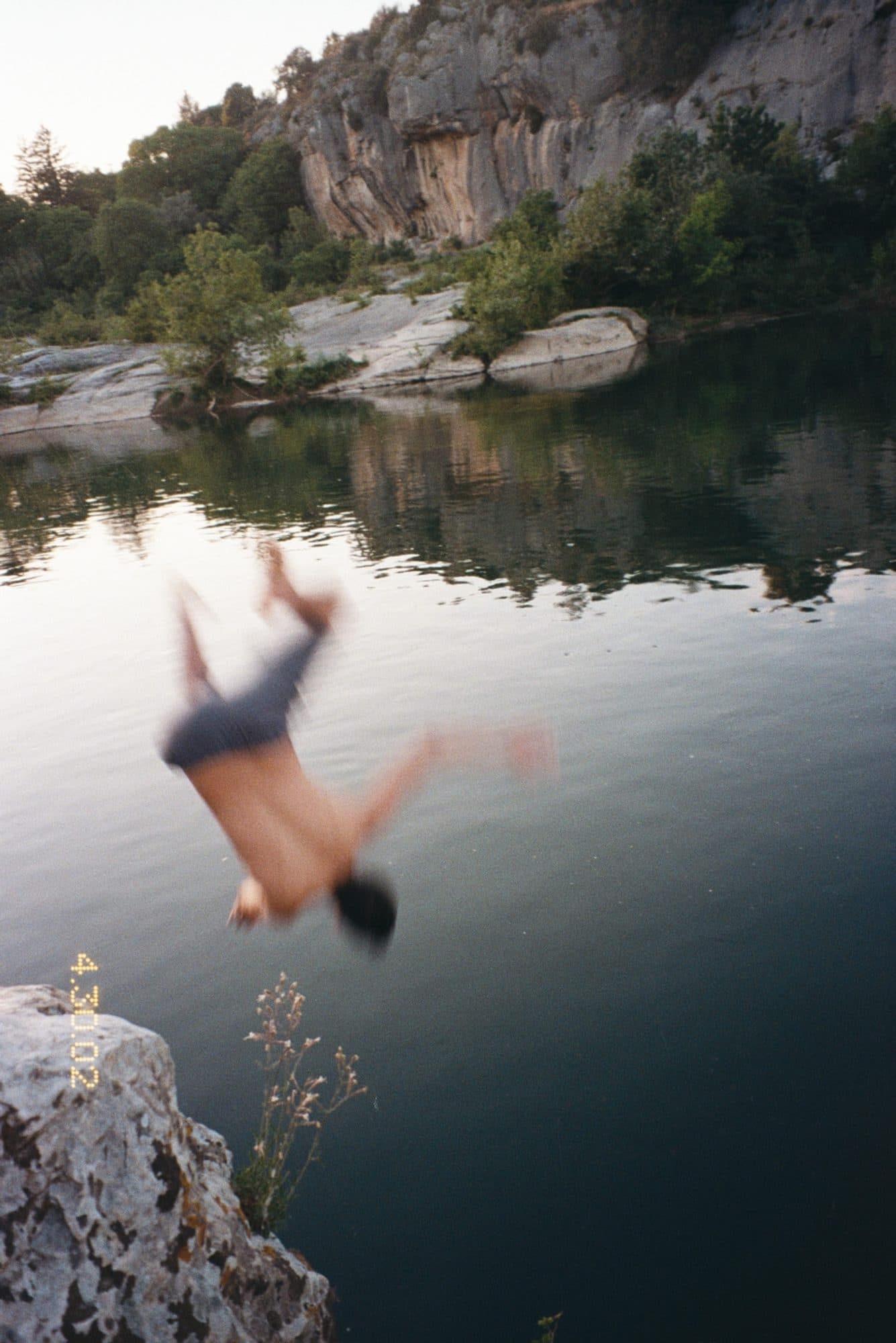 Backflip dive into a river below limestone cliffs